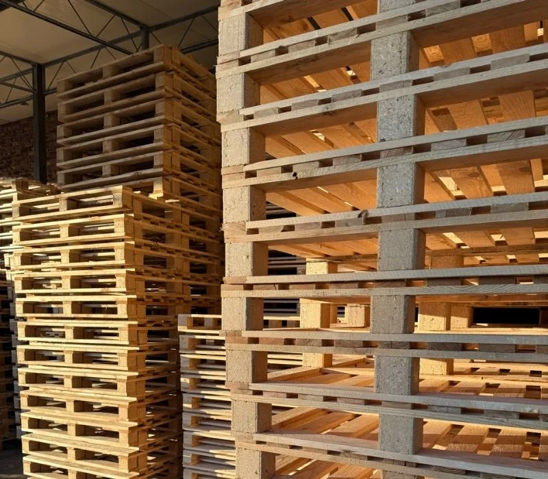 Wysokie stosy nowych palet drewnianych w magazynie certyfikowanego producenta palet HGV