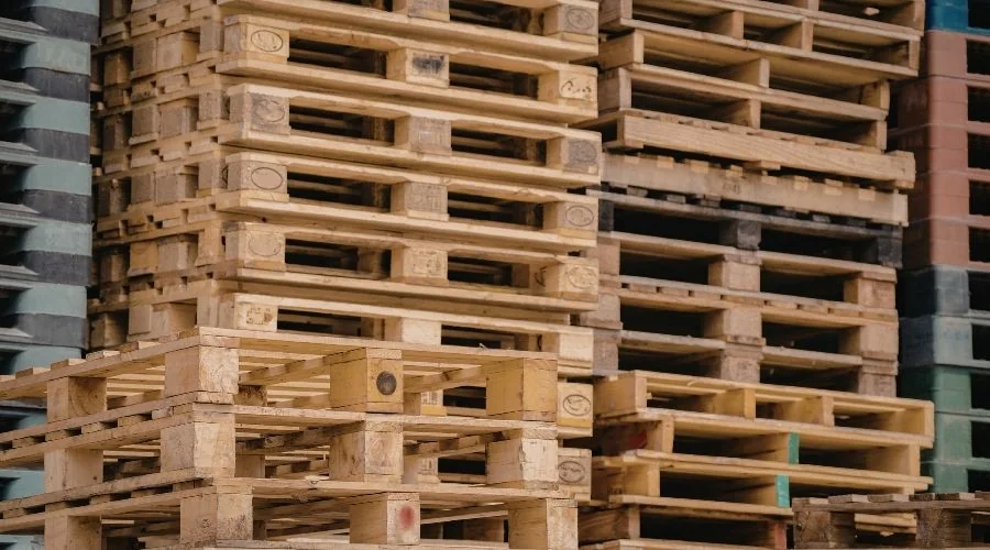 Stos nowych palet drewnianych w magazynie od producenta HGV