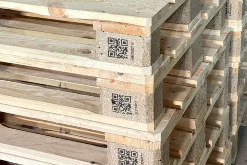 Producent palet drewnianych Kutno - stos nowych palet z kodami QR